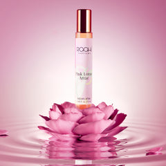 A slender transparent glass bottle with rose gold cap and label containing amber pink lotus attar by raah parfums 12ml