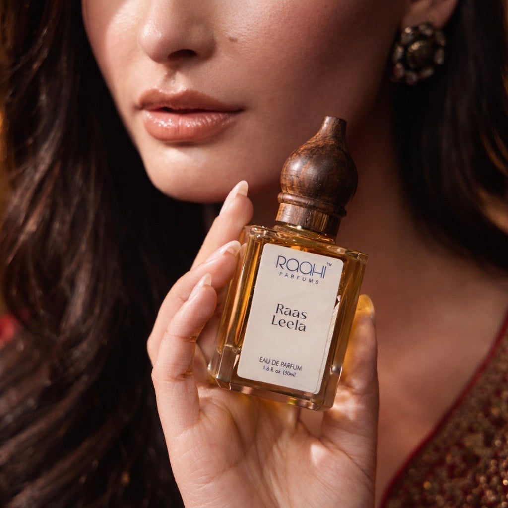 A rectangular amber glass perfume bottle with a dark brown wooden stopper labeled roohi parfums raas leela eau de parfum 50ml