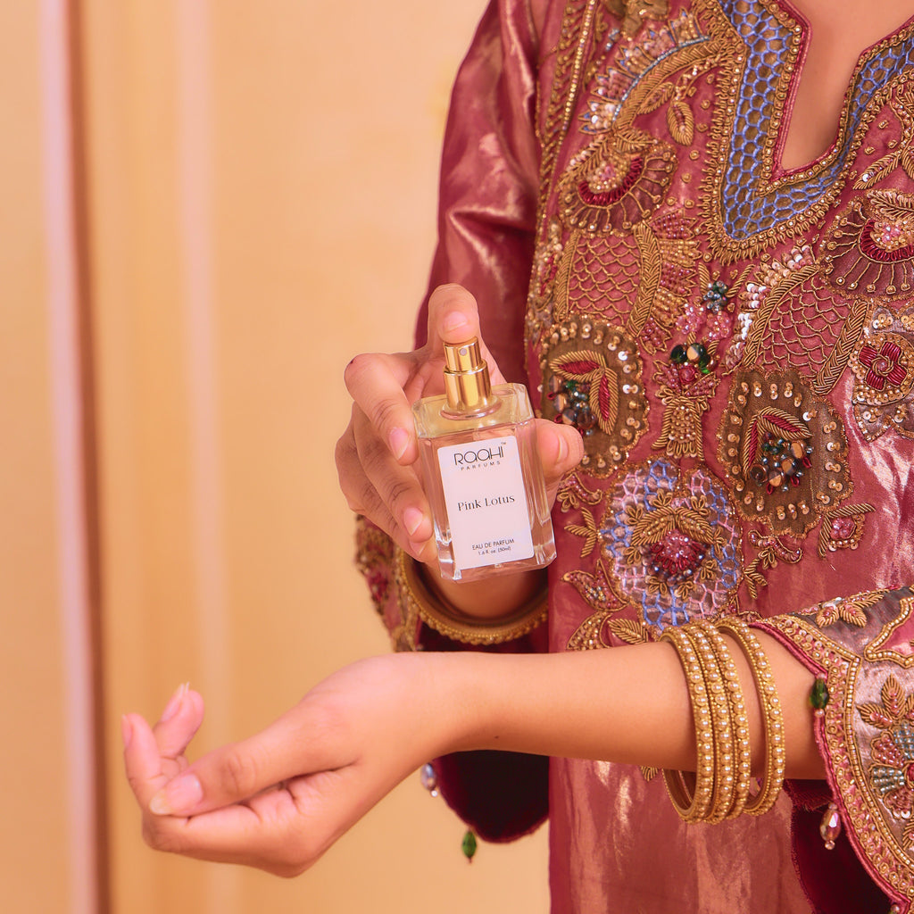 A clear glass bottle of poochi parfum pink lotus eau de parfum 50ml with gold-tone spray nozzle and minimalist white label