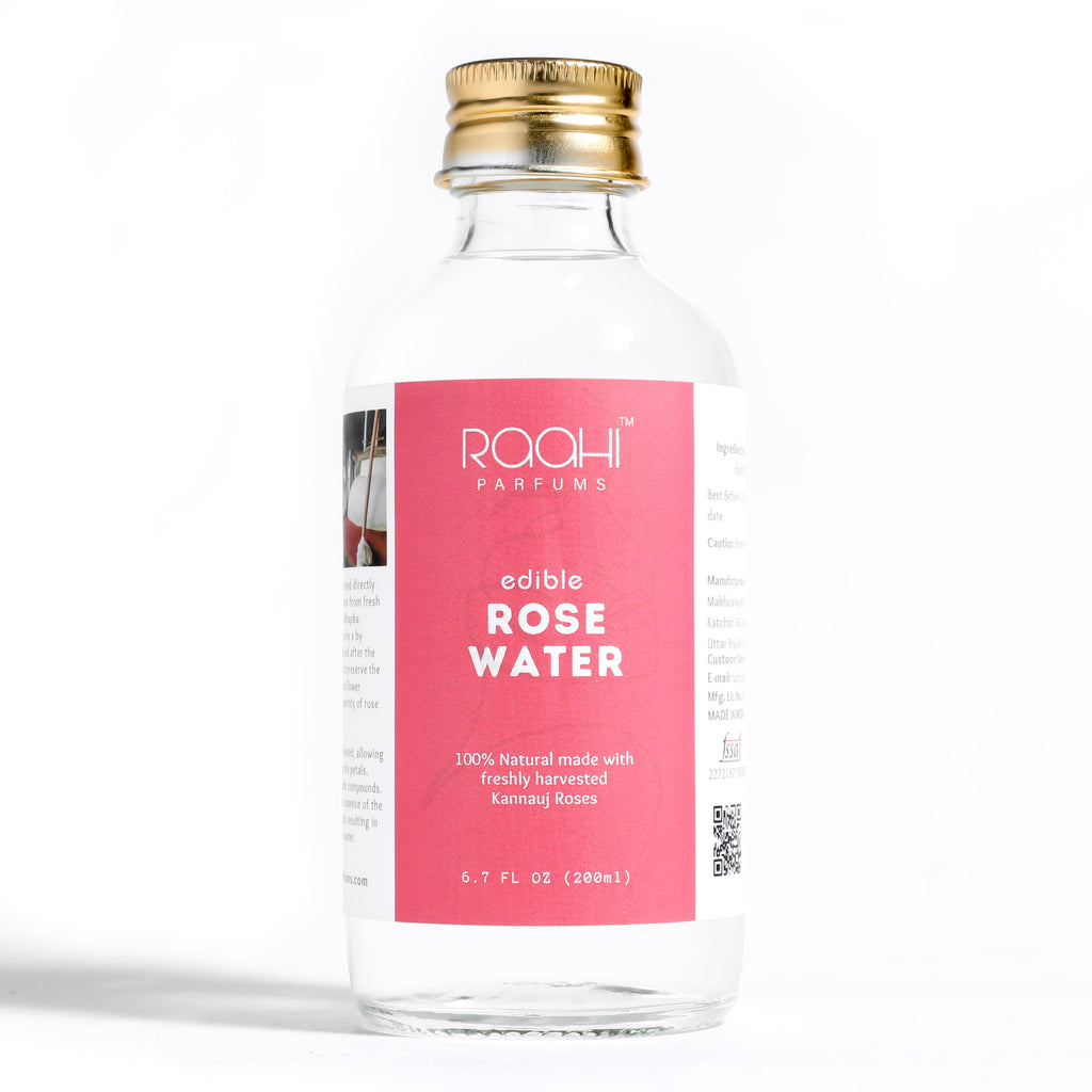 A clear glass bottle of rooahi parfums edible rose water with a gold cap and pink label made from kannauj roses