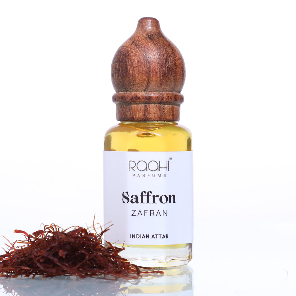 A clear glass bottle with polished wooden stopper containing golden-yellow saffron attar by raahi parfums handcrafted in Kannauj