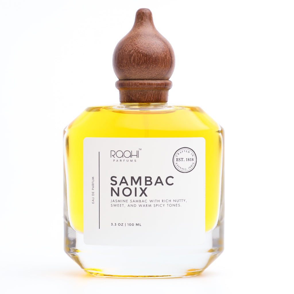 A clear glass bottle with a wooden stopper filled with golden-yellow sambac noix eau de parfum by roohi parfums