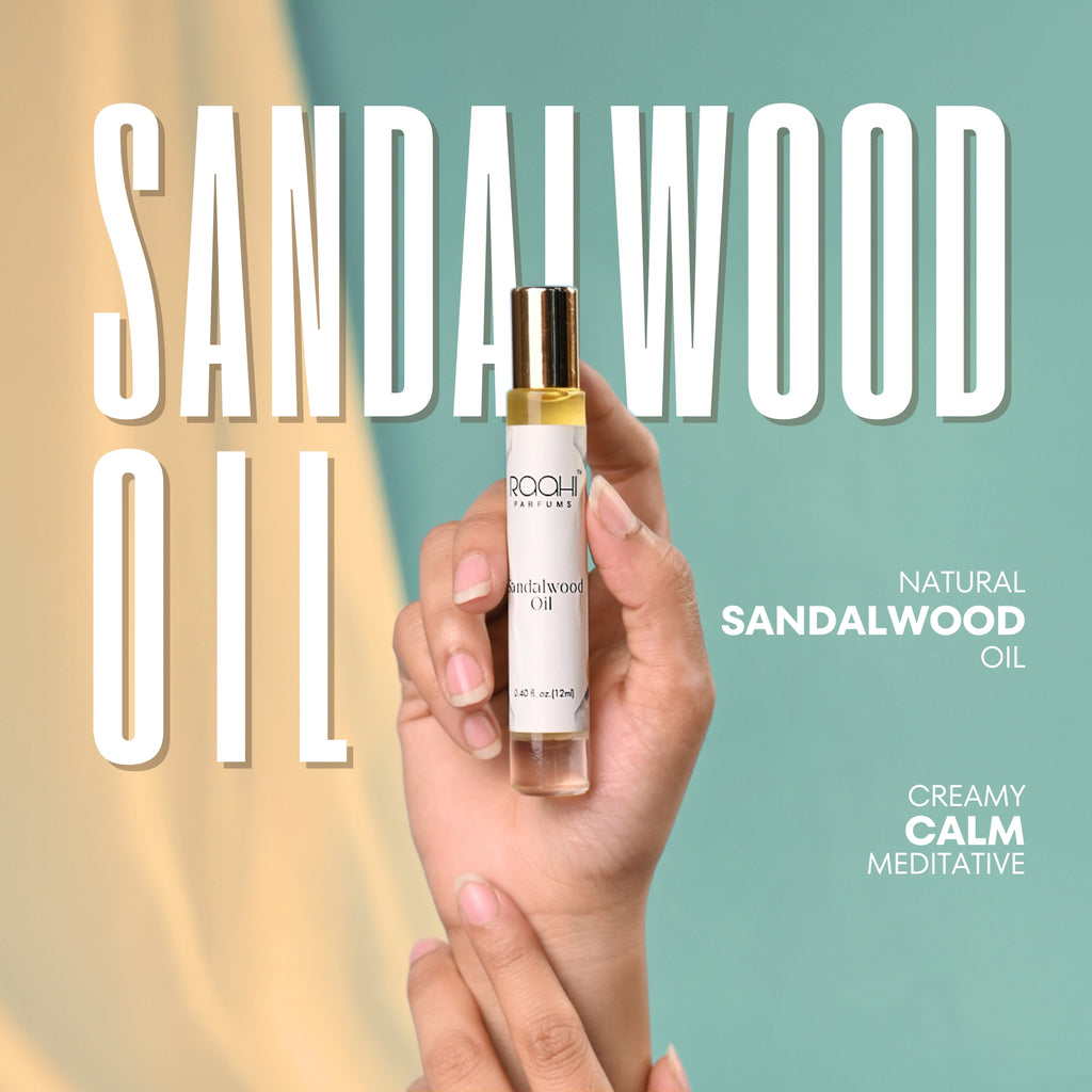 A sleek transparent glass bottle with gold cap holds golden sandalwood oil from Roohi Parfums 100% pure