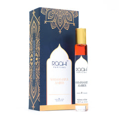 A sleek transparent glass rollerball bottle with gold cap and amber shamamatul amber attar by roahi parfums