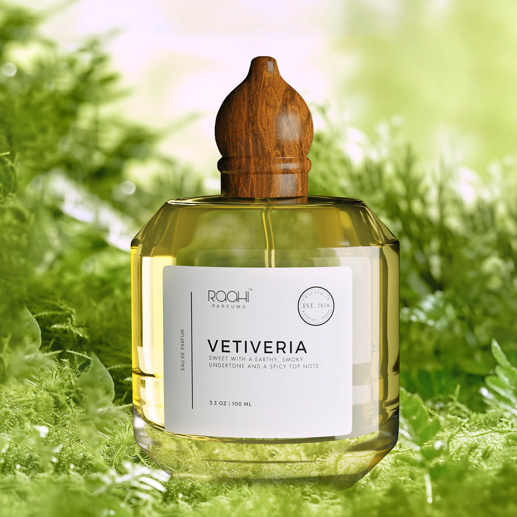 A clear glass bottle of Rqohi Parfums Vetiveria eau de parfum with a polished wooden cap and golden-yellow liquid