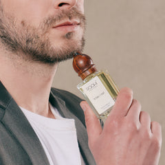 A clear glass bottle of Roahi white oud eau de parfum with a polished wooden stopper and label in 50ml size